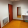 Toilettes avec porte rouge, lavabo, distributeur de savon, sèche-mains et radiateur.