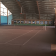 Salle intérieure avec terrain de tennis, cibles de tir à l'arc, table et chaises.