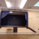 Salle avec scène, écran, projecteur, tabourets, climatiseurs et lumières.