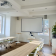 Salle avec tables, chaises, projecteur, écran, ordinateur et plantes.