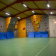 Salle d'escalade avec murs d'escalade, tapis de sécurité, sol vert et éclairage.