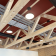 Poutres en bois, plafond rouge, lumières, conduits noirs.