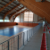 Salle de sport avec terrain, paniers, gradins et filet de volley.