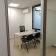 Bureau avec table, chaises, ordinateur, porte vitrée et climatiseur.
