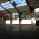 Salle spacieuse avec sol en parquet, vitres, portes en bois et toit en verre.