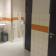 Toilettes avec lavabo, urinoirs, distributeur de savon et poubelle. Porte avec symbole handicapé.