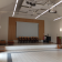Salle avec écran, chaises, pupitre, projecteur et matériel audio.