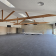 Salle avec poutres en bois, écrans, tables pliables et rangées contre le mur.