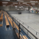 Patinoire avec gradins, surface de glace, filet et panneaux publicitaires.