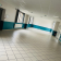 Salle vide avec carrelage, murs teintés, portes et plafond à dalles.