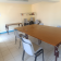 Salle avec table, chaises, étagère et climatiseur mural.