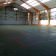 Salle de sport avec terrain de basket, panier, grandes fenêtres et structure métallique.