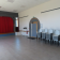Salle avec rideau rouge, porte, chaises empilées et extincteur.