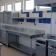 Cuisine professionnelle avec plans de travail, évier, plaques de cuisson, étagères et hottes.