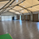 Salle spacieuse avec plancher en bois, murs blancs, rideaux, portes et un tapis vert.