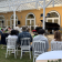 Concert en plein air avec piano, chaises, public et structure vitrée.