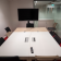 Salle de réunion avec table, chaises, écran, télécommande et armoire.