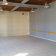 Pièce vide avec carrelage, murs peints, plinthes, prises électriques, interrupteurs, plafond avec poutres apparentes et suspensions.
