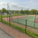 Tennis avec clôture, terrain, filet, bâtiment et route.