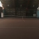 Terrain de tennis intérieur avec filet, murs bleus, toit métallique, échelle et panneau.