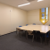 Salle de réunion avec table, chaises, tableau blanc et fenêtre.