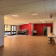 Salle avec tables, chaises, tableau blanc, équipement audio et éclairage au plafond.