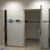 Toilettes avec portes ouvertes, urinoirs, toilettes, lavabo et panneaux indicateurs.