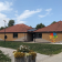Bâtiment avec toit rouge, murs en bois, panneaux solaires, vélo, graffiti, fleurs et réverbère.