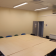 Salle avec table, chaises, climatiseur, lumières, porte, radiateur et affichages muraux.