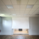 Salle avec projecteur, écran, parquet et murs blancs.