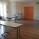 Salle avec tables, chaises, portes orange et murs en pierre.
