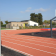 Stade avec piste d'athlétisme, panier de basket et abris.