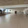 Salle vide avec sol carrelé, portes, fenêtres et distributeur automatique.