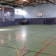 Salle de sport avec paniers de basket, filet de handball et gradins.