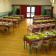Salle avec tables, chaises, nappes, sets de table, verres et fleurs.