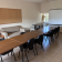 Salle avec table, chaises, canapé, tableau d'affichage et écran.