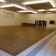 Salle avec plancher en bois, bancs, portes et éclairage encastré.