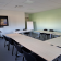 "Salle de réunion avec tables en U, chaises, écran et tableau blanc".
