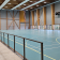 Salle de sport avec terrain, gradins, panier de basket et filet de foot.