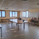 Salle avec tables, chaises, tableau blanc, fenêtres et équipement informatique.