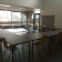 Salle avec tables en L, chaises et portes vitrées.