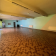 Salle vide avec parquet, murs peints, radiateurs et porte.