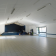 Salle spacieuse avec sol carrelé, murs blancs, plafond suspendu, éclairage, porte vitrée et mur bleu.