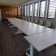 "Salle avec longues tables, chaises, fenêtres et affichages muraux."