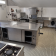 Cuisine avec plans de travail en acier inoxydable, éviers, plaques de cuisson, étagères et armoires.