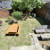 Cour avec banc, palettes, table ronde, arbre et murs en brique.
