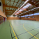 Salle de sport avec panneaux, terrain, gradins, paniers de basket.