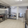 Cuisine professionnelle avec fourneaux, hottes, réfrigérateurs, étagères et plans de travail en acier inoxydable.