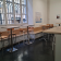 Salle avec tables, tabourets, chaises, vitres et luminaire rond au plafond.