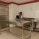 Cuisine avec four, table en acier, micro-ondes, plaque de cuisson et plan de travail.